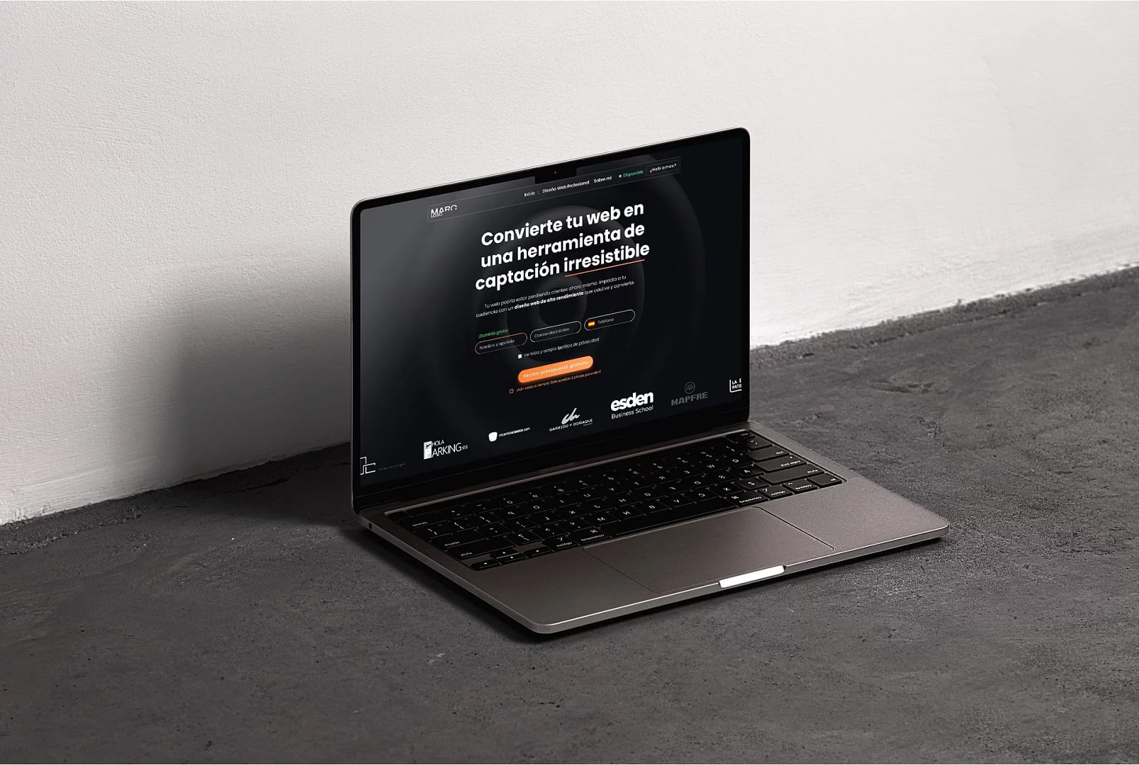 Marc Loic | Agencia de Diseño Web en Madrid 🏅 32 Laptop en suelo gris con pantalla negra mostrando diseño web profesional para captación de clientes en Madrid.
