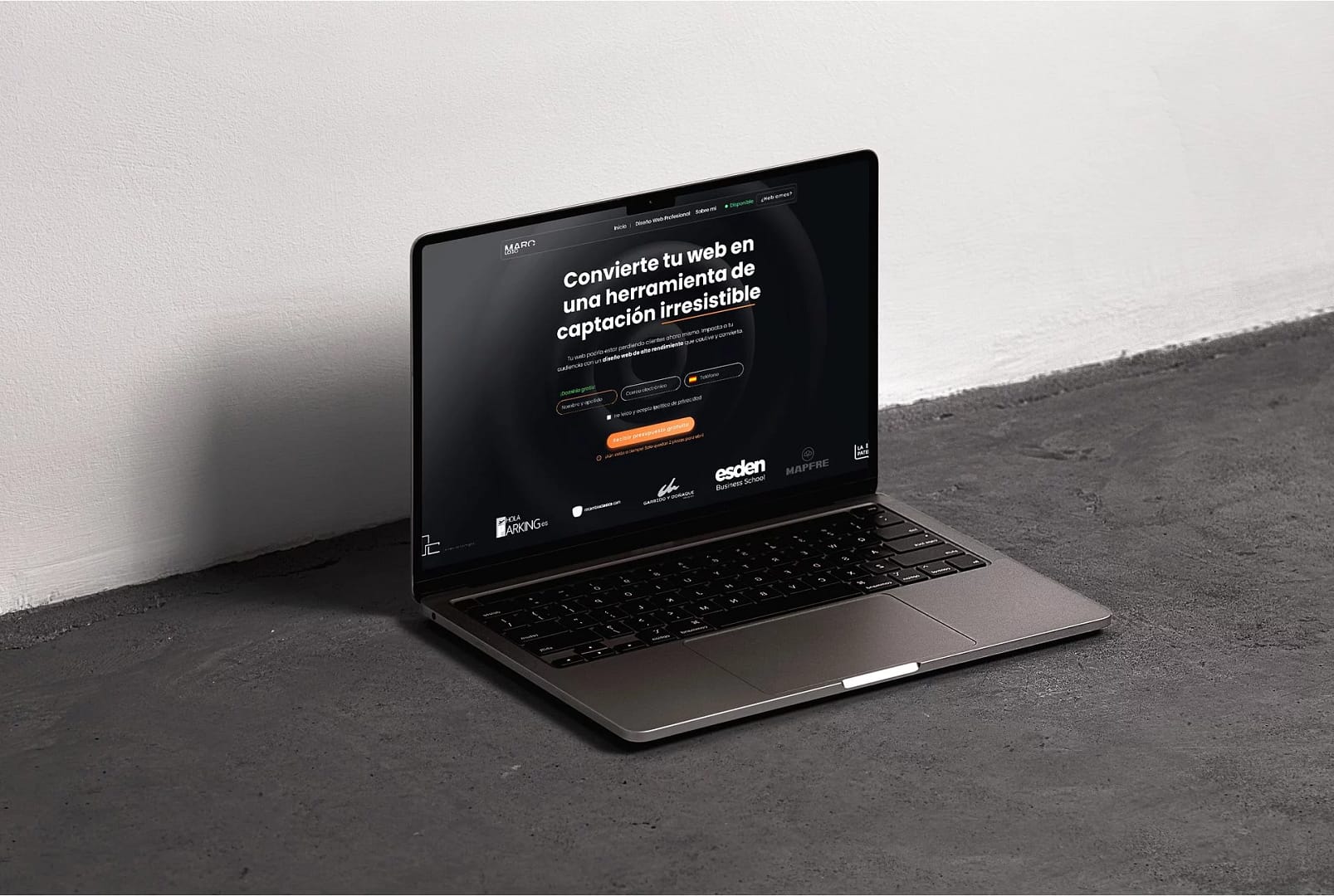 Agencia especialista de Diseño Web en Madrid | Marc Loic 32 Laptop en suelo gris con pantalla negra mostrando diseño web profesional para captación de clientes en Madrid.